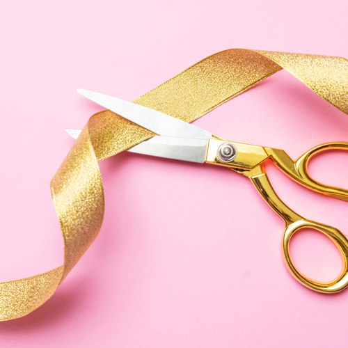 gold scissors cutting gold ribbon